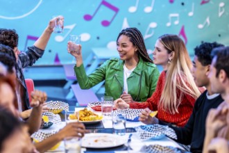 Multiethnic friends enjoying a meal and drinks at a bowling alley restaurant, celebrating their