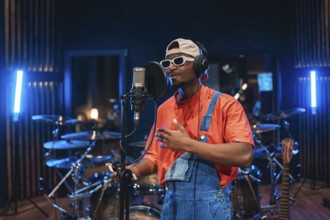 Young man singing into microphone, recording vocals for new album in professional music studio