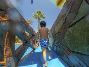 Child running through a water park during summer vacation in alicante, spain, enjoying the