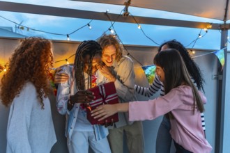 Happy millennial multi-ethnic friends celebrating birthday party in an urban rooftop at dusk