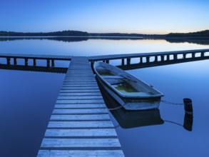 Wooden jetty with rowing boat at dusk, after sunset on Lake Schaalsee, Mecklenburg-Western