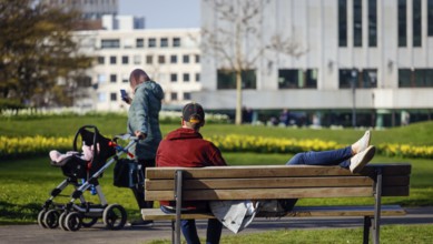 A couple relaxing on a park bench in the city garden in times of the corona crisis, Essen, Ruhr