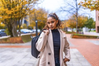 Young african american businesswoman carrying laptop bag walking along the city in autumn