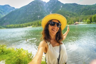 Happy tourist taking a selfie with outstretched arms at lake dobbiaco in the italian dolomites,