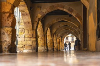 Tourists walking through the arches of the medieval city of tarragona, spain, enjoying the