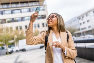 Dynamic shot of a happy latin woman walking along the city taking photos