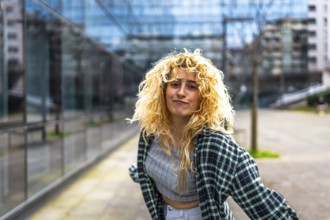 Caucasian woman with curly blonde hair joyfully dancing to modern urban music in the vibrant city,