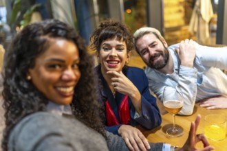 Latin woman and friends taking selfie while sitting on bar enjoying beer together