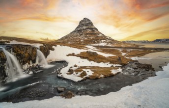 Beautiful sunrise on the famous Kirkjufell mountain next to the waterfall in winter in Iceland