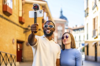 Multi-ethnic couple broadcasting with mobile phone and mic in the city