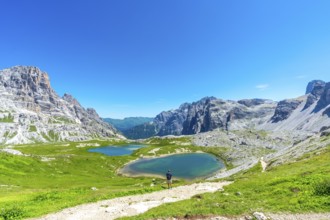 Breathtaking view of the tre cime di lavaredo and the surrounding lakes with a tourist enjoying the