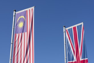 Malaysia and British flags fly against a clear blue sky