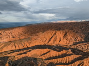 Landscape of eroded hills, badlands at sunset, Issyk Kul Lake in the background, aerial view,