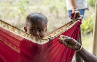 Children of tea plantation workers takes care by daycare worker underneath a tent as their mothers