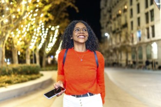 Young woman enjoying an evening stroll through a vibrant, illuminated city, engaging with her