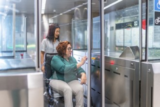 Disabled woman and chinese caregiver at the entrance of the metro introducing the ticket at the