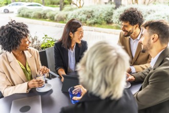 Multi-ethnic business people drinking coffee working with digital tablet sitting relaxed in a