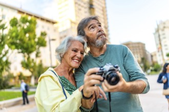 Senior modern caucasian couple taking photos while visiting a city together
