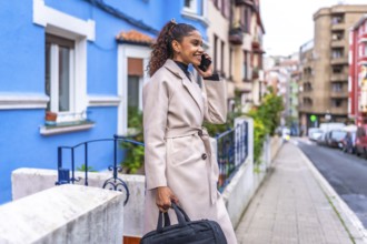 Side view of a beauty young Afro american businesswoman talking to the mobile walking at city