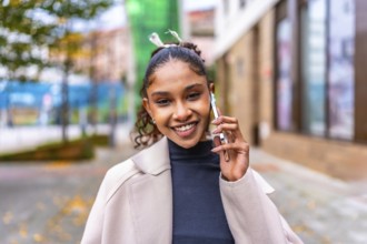 Happy african elegant woman talking to the mobile phone standing in the city street