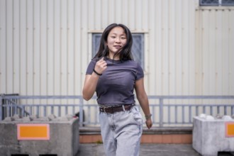 Passionate asian woman dancing k-pop choreography in the city next to an industrial building