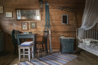 Interior of a traditional Norwegian wooden storehouse or Stabbur with old furniture and skis on the