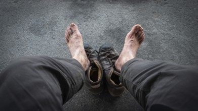 View of two bare feet of a pilgrim, worn hiking boots on dark ground, pilgrimage route Olavsweg or
