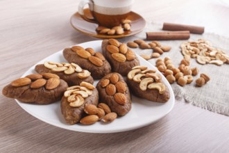 Small cakes potatoes with almonds and cashew nuts on a dessert plate. A cup of coffee, cinnamon,