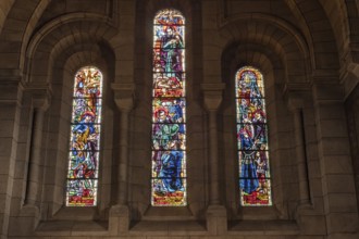 Three stained glass windows in a church, illuminated with various religious scenes, Paris