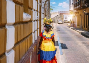 Colombia, lady in national colorful costume walking the streets of Walled City historic center of