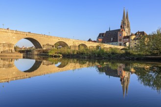 Church and bridge reflected in river, evening light, sunny, idyllic, Regensburg Cathedral and stone