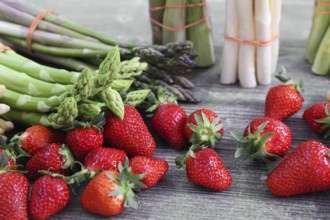 Green asparagus, white asparagus and fresh strawberries decorated on a rustic wooden table