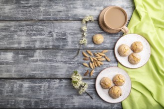 Almond cookies and a cup of coffee on a gray wooden background and green linen textile. Top view,