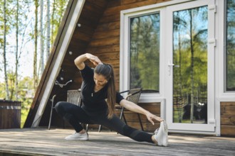 Sporty woman doing side slopes on terrace of bungalow
