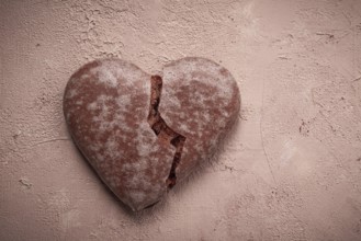 Glazed chocolate gingerbread, heart-shaped, top view, a broken heart, close-up, on beige
