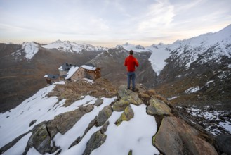 Hiker looking at mountain panorama and glacier, mountain hut Ramolhaus in autumn with snow, at