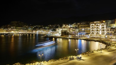 Harbour at night with illuminated buildings, lights reflected in the calm water, Pigadia, town and
