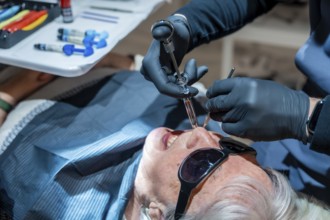 Dentist wearing black gloves injecting anesthesia to senior woman patient before dental procedure