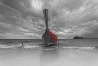 Longtail boat on the beach, dark rain clouds behind, Koh Ngai Island, Andaman Sea, Satun Province,