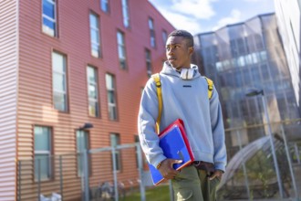 Confident african student wearing hoodie and urban clothes standing outside the university