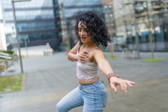 Curly haired woman dancing to lively latin music in an urban city center, soaking up the sun and