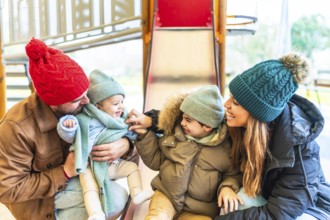 Cheerful family bundled in winter clothes enjoying quality time together while sliding down a
