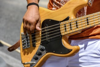 Hands playing an electric bass guitar on the street in a sunny day, Minas Gerais, Brazil, South