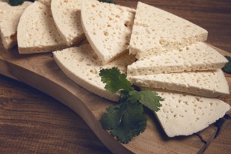 Sliced Georgian cheese, factory grade, on a wooden board, top view