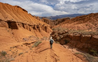 Mountaineer on a mountain ridge, view of eroded mountain landscape with sandstone cliffs, canyon