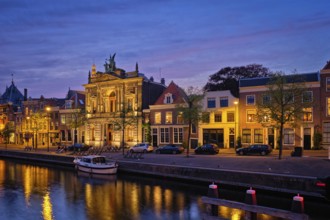 Canal with boats and houses illuminated in the evening. Haarlem, Netherlands