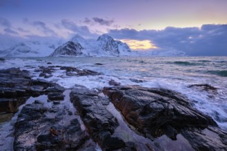 Beach of Norwegian sea on rocky coast in fjord on sunset in winter. Vareid beach, Lofoten islands,