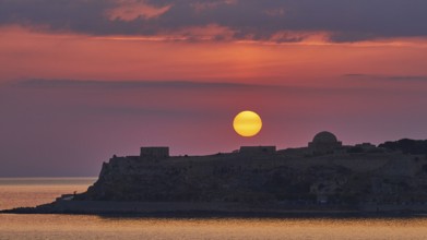 Sunrise, orange sunball over Venetian fortress, red sky, grey clouds, silhouette, backlight,