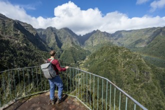 Tourist at a viewpoint, view from the Miradouro dos Balcões, densely overgrown steep mountains,