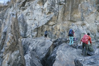 Climbers preparing for ascent. Three male female persons walking on the rocks. Extreme outdoor